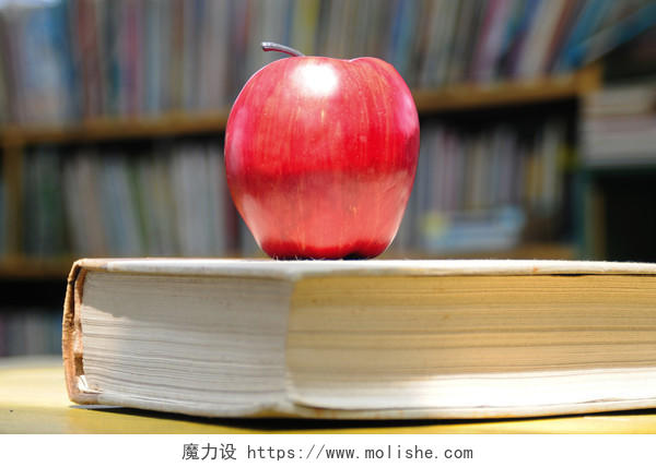 一本厚书上的一个红苹果读书分相会阅读世界读书日